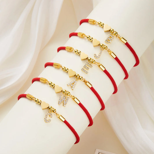 detail charm coeur initiale bracelet cordon rouge